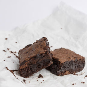 Two chocolate brownies with fudgy texture on white background