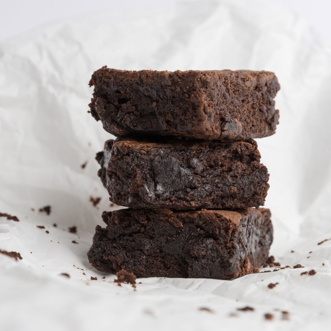 Stack of rich chocolate brownies on white paper