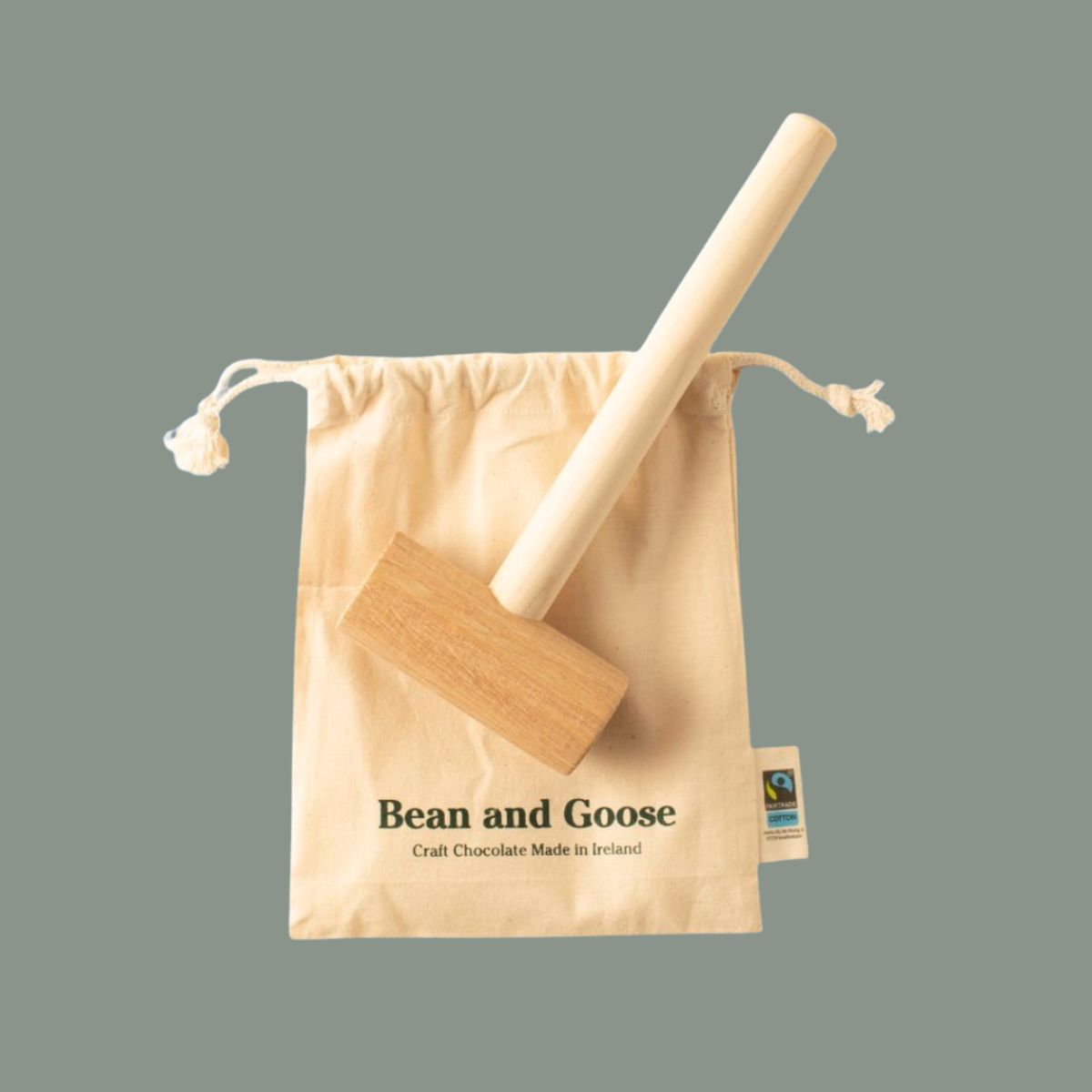 Wooden hammer of joy on a 'Bean and Goose' branded drawstring bag against a gray background.