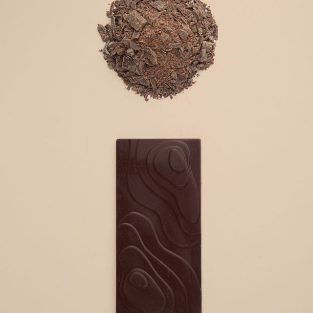 Bean and Goose dark chocolate bar with a scoop of dark chocolate shavings on a beige background