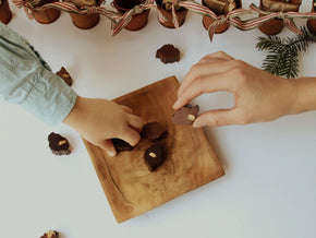 “Hands reaching for handcrafted Bean and Goose chocolate islands during the Advent countdown.”