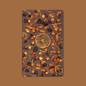 Chocolate bar with dried fruits and a central round piece on a brown background